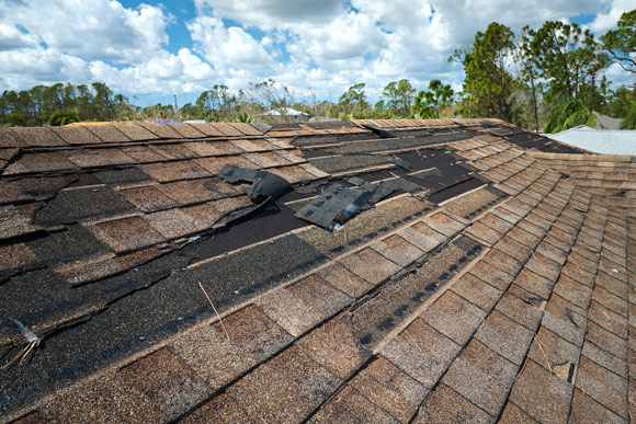 broken roof tiles on top of property against blue clouded sky