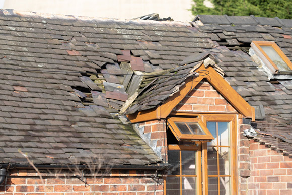 storm damaged roof of house slipped tiles above roof window