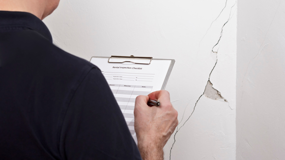 inspection of property being undertaken against cracks in wall of rental